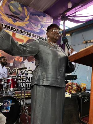 Smiling woman holding a food box from Lagos Food Bank on a busy street in Lagos, Nigeria.